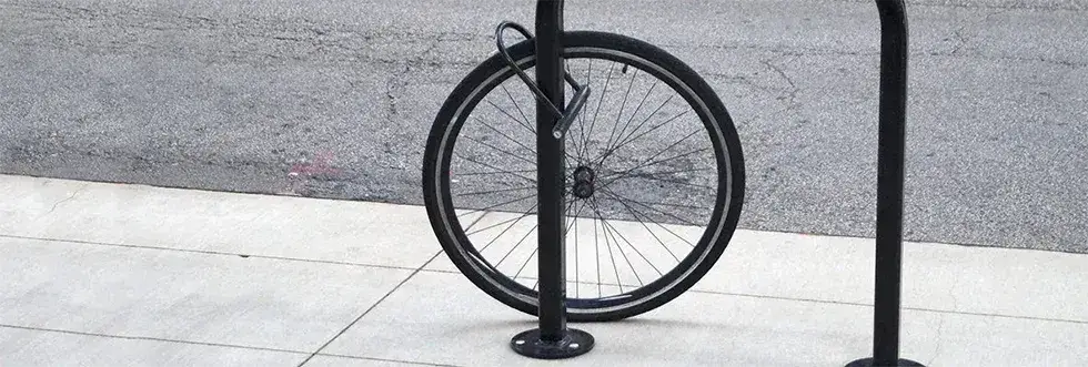 Image of a bicycle wheel at the roadside locked to a bicycle stand