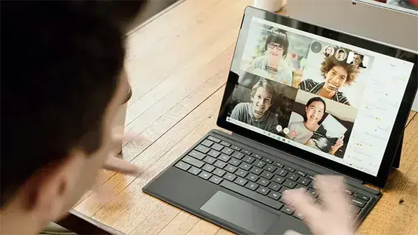 Young professional speaking with multiple colleagues over video call on a laptop