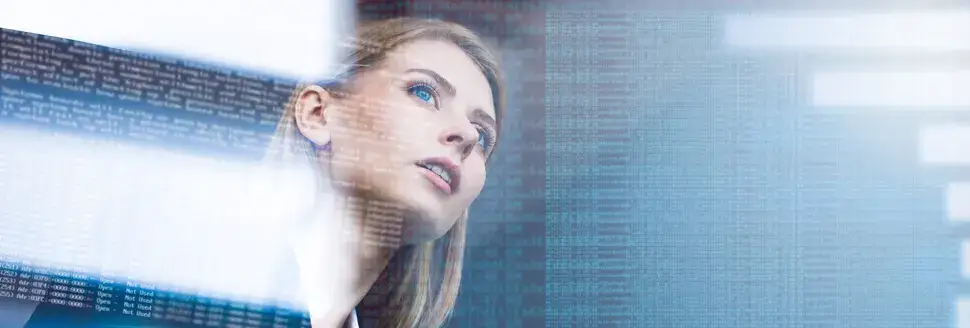 Young woman inspecting data on a translucent digital display in a dimly-lit office space