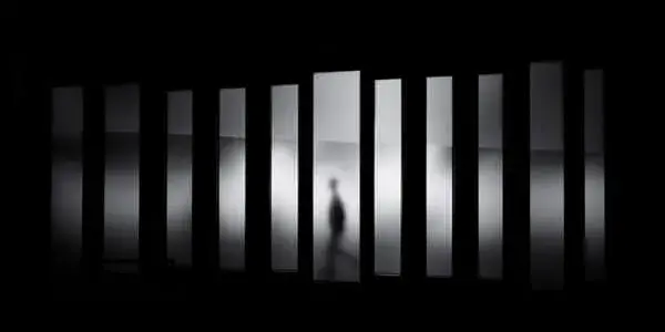 Person walking behind a dark screen