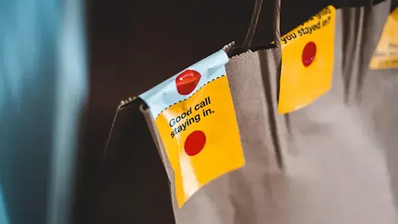 Close-up shot of brown paper takeaway bags with brightly-coloured sticker seals on them