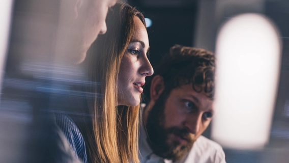 Team of young business professionals seated around a desk viewing an off-screen display