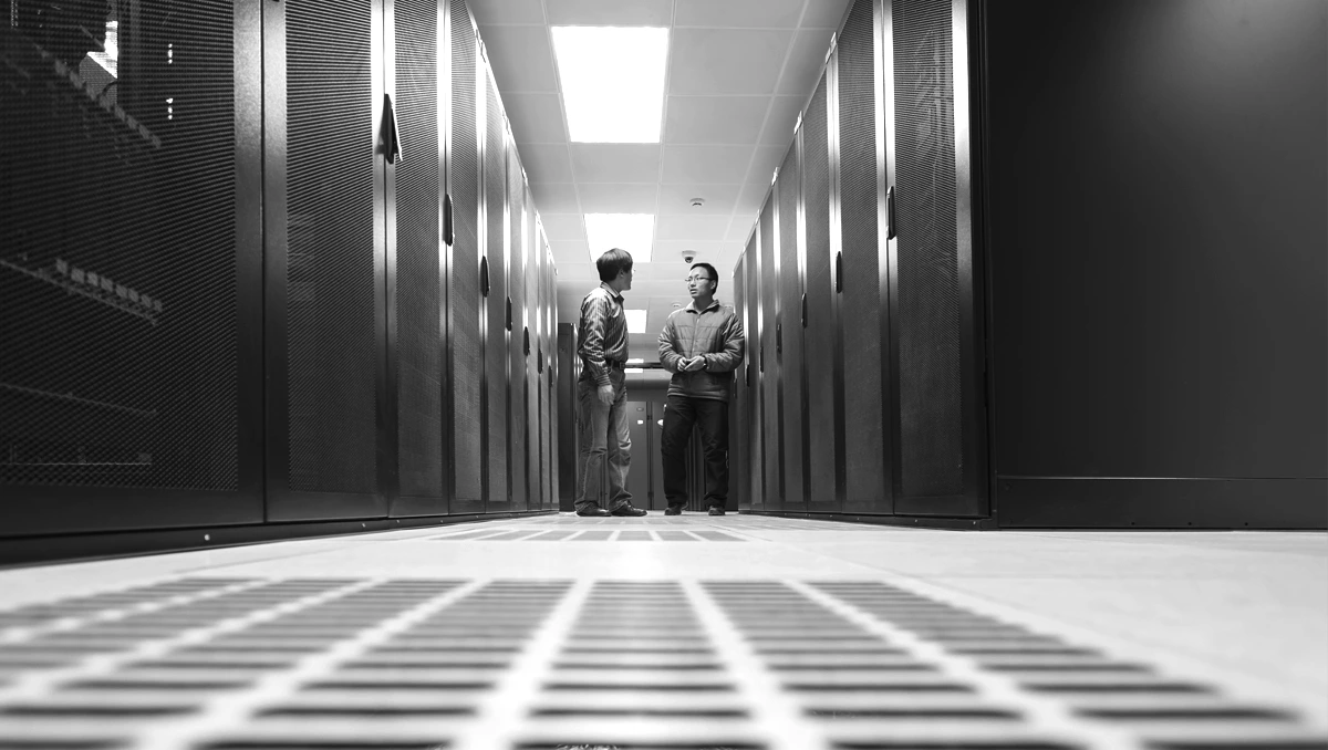 Black and white image of two IT professionals standing in a data center