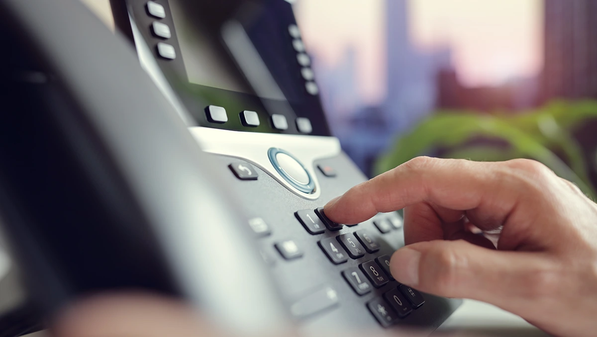 Closeup image of businessman using a VoIP Handset in office environment