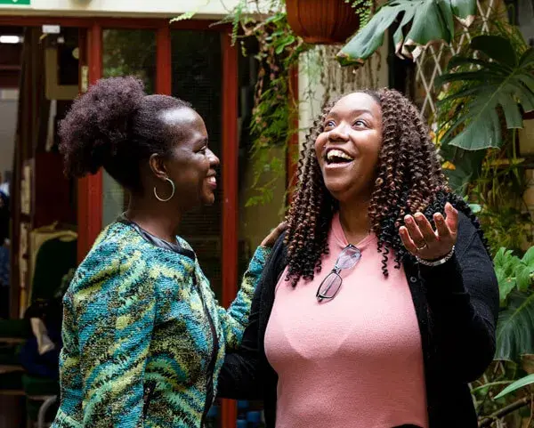 Two women talking and laughing in an open courtyard area